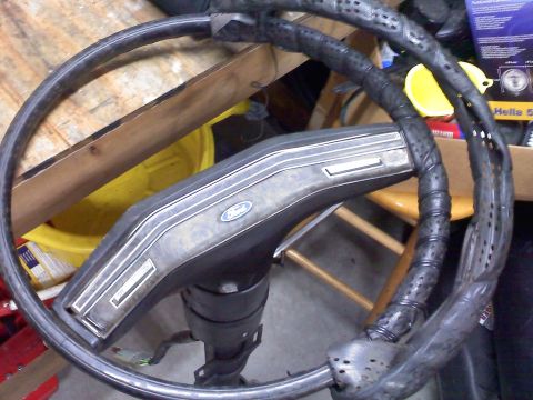 1977 Ford F-100 - Close-up of a Ford steering wheel, showing the central hub with the Ford emblem and the wrapped steering column.