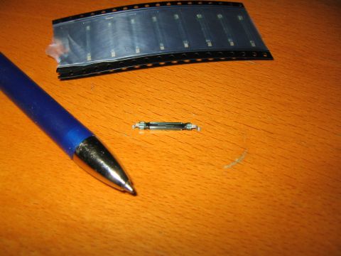2009 Suzuki Samurai - A small electronic component, possibly a reed switch, is shown next to a blue pen and a reel of electronic parts.