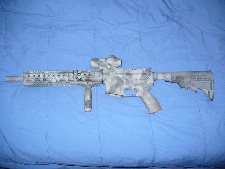 White winter-camo AR-style rifle with quad rail, foregrip and red-dot optic on a blue sheet