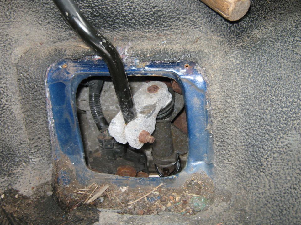 Gear shifter mechanism in a blue metal housing with dirt and debris
