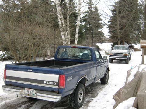 1996 Ford F-150 - A blue 1996 Ford F-150 pickup truck is parked in a snowy driveway, with another truck visible in the background.