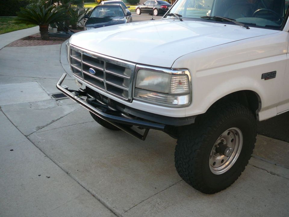 Front end of a white Ford F-Series truck with a chrome grille and aftermarket bumper