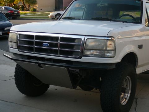 1988 Ford Bronco - Frontal view of a white Ford truck with a prominent chrome grille and a custom bumper.