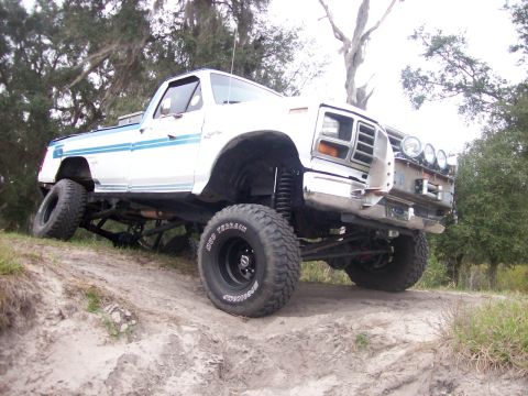 1982 Ford F-100 - This lifted pickup truck is equipped with off-road tires and auxiliary lights on the front bumper.