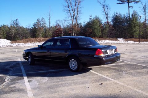 2001 Ford Crown Victoria - A black 2001 Ford Crown Victoria is parked in a lot on a clear day.