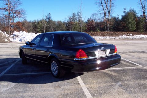 2001 Ford Crown Victoria - A black 2001 Ford Crown Victoria is parked in an outdoor lot under a clear sky.