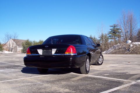 2001 Ford Crown Victoria - Rear view of a black 2001 Ford Crown Victoria sedan parked outdoors on a sunny day.