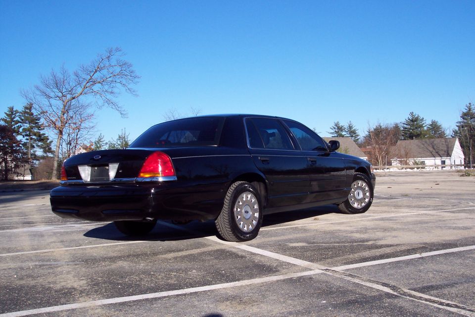 Black 2001 Ford Crown Victoria parked in an empty lot under a clear blue sky