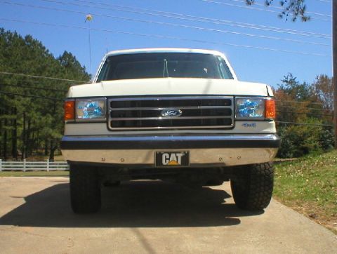 1989 Ford Bronco - White Ford F-Series truck, likely a 1987 model, seen from the front with a CAT emblem.