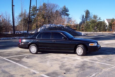 2001 Ford Crown Victoria - Side view of a black 2001 Ford Crown Victoria sedan in a parking lot on a sunny day.