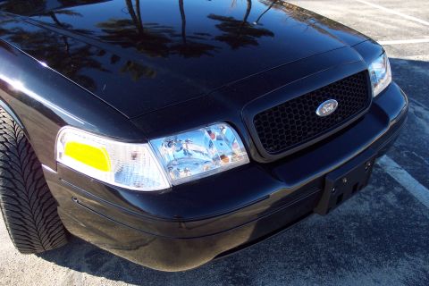 2001 Ford Crown Victoria - Front end of a black 2001 Ford Crown Victoria with a honeycomb grille and clear headlights.