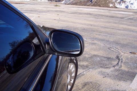 2001 Ford Crown Victoria - A black car is parked in an empty lot with snow in the background.