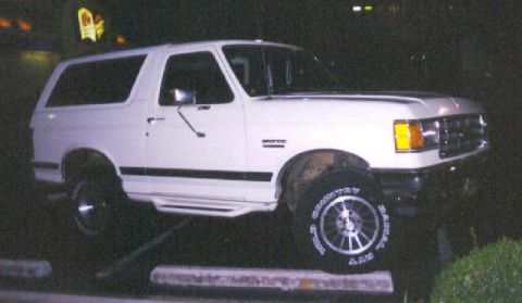 1989 Ford Bronco - A white Ford Bronco is parked at night, with its front and side visible.