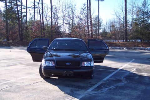 2001 Ford Crown Victoria - Front view of a black 2001 Ford Crown Victoria parked in a lot with its front and rear doors open.