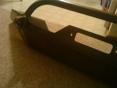 1995 Ford Bronco - Black powder-coated aftermarket front bumper with brush guard hoop laid on garage floor.