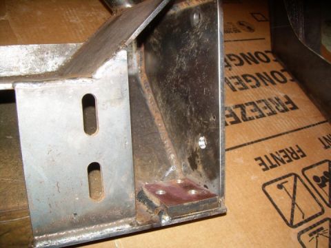 1995 Ford Bronco - Close-up of a metal bracket with slotted holes and a welded plate, resting on cardboard packaging.