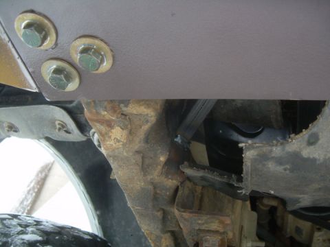 1995 Ford Bronco - Low-angle underside shot of a newly installed steel bumper, showing the gray-painted bumper skin bolted through a bracket with three large…