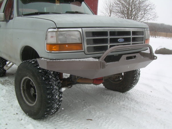 Custom bare steel front bumper with grille hoop on a gray Ford truck in snow