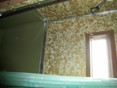 1985 Ford Bronco - The interior of a vehicle shows patterned wallpaper, a shower head, and a window, with a "SUPERMOTORS" watermark.
