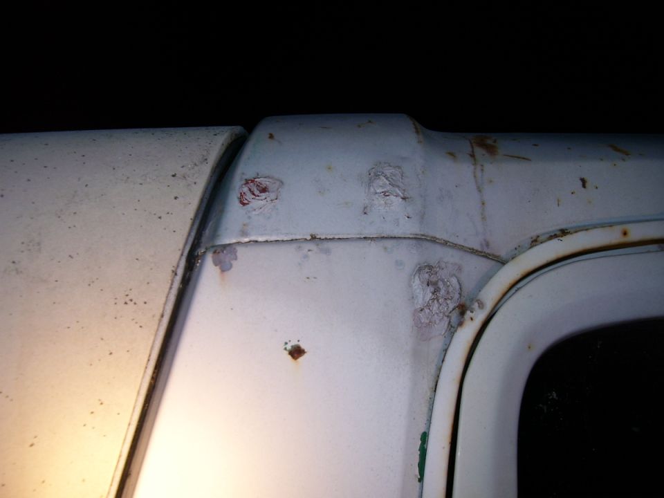 Close-up of white Bronco roof pillar with body filler patches, rust spots and stains near rear window