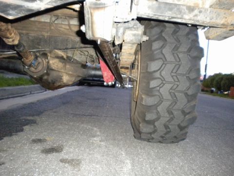 1989 Ford Bronco - Close-up of a vehicle's undercarriage, focusing on the rear axle and tire assembly.