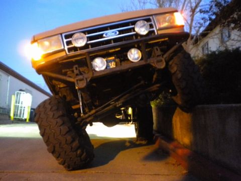 1989 Ford Bronco - This modified Ford Bronco is shown with its front wheel on a raised surface, highlighting its off-road capabilities.