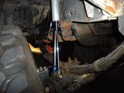 1989 Ford Bronco - This image shows the underside of a vehicle, focusing on the suspension system and a large tire, with visible rust on the frame.