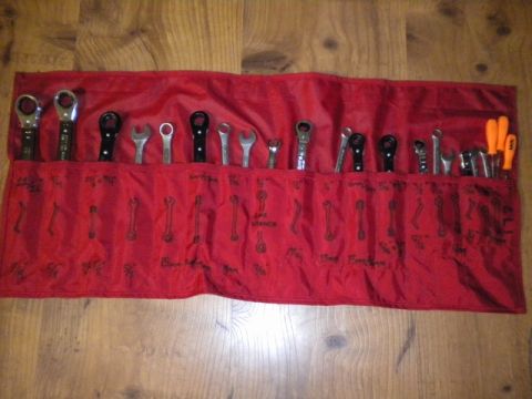 1989 Ford Bronco - A red fabric tool roll is spread open, displaying a collection of wrenches and screwdrivers organized in individual pockets.