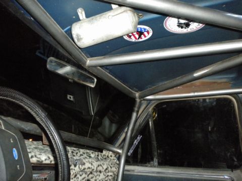 1989 Ford Bronco - The interior of a vehicle is shown, a prominent roll cage and unique leopard print seat covers.