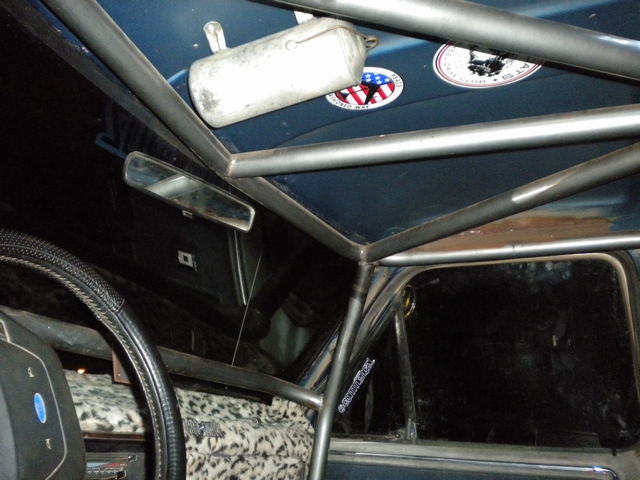 Bare steel roll cage and overhead fire extinguisher inside a blue Ford truck cab