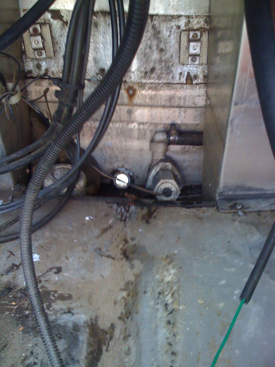 Boat bilge pump with wiring and hoses in a dirty compartment
