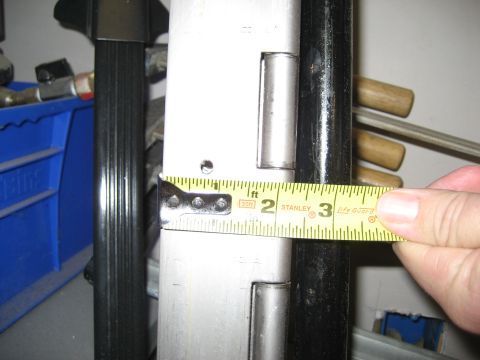 1996 Ford Bronco - Close-up of a measuring tape on a white metal surface with hinges, indicating a measurement.