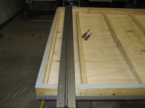 1996 Ford Bronco - A close-up view of a wooden surface with a large metal hinge and two screwdrivers.