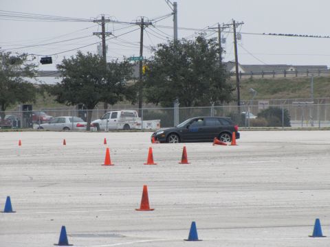 2003 Mazda Protege - A dark station wagon navigates a course marked by traffic cones, with other vehicles visible in the background.