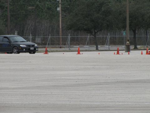 2003 Mazda Protege - A black sedan navigates a course marked by orange cones on a paved lot.