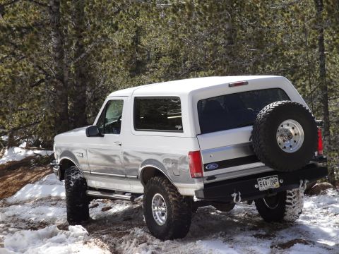 1995 Ford Bronco - This 1995 Ford Bronco is shown in a snowy, wooded area, a spare tire mounted on the rear.