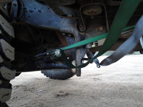 1995 Ford Bronco - Tie-down straps securing the undercarriage of a vehicle for transport.
