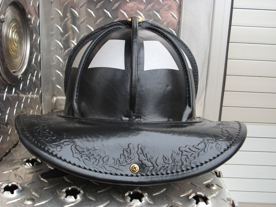 Black leather firefighter helmet on diamond-plate metal surface