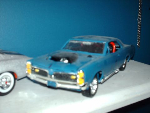 1978 Ford Mustang II - A blue toy car with a black hood scoop sits next to another toy car on a shelf.