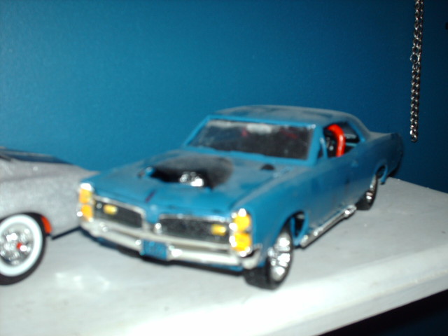 Blue toy car with black hood scoop and red interior, viewed from a 3/4 front angle