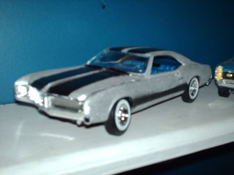 1978 Ford Mustang II - A silver coupe with black racing stripes and a blue interior is shown next to another vehicle.