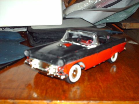 1978 Ford Mustang II - A two-tone model car sits on a reflective wooden table, with a white object and papers in the background.