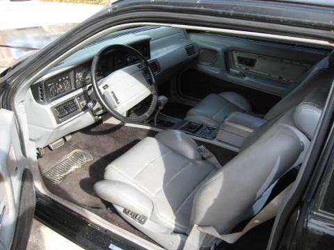 1990 Lincoln Mark VII - The interior of the car shows gray leather seats and a dashboard with various controls and gauges.