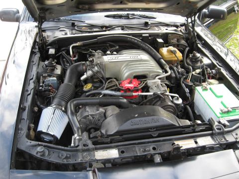 1990 Lincoln Mark VII - The engine bay of a 1990 Lincoln Mark VII is displayed, a V8 engine with custom modifications.