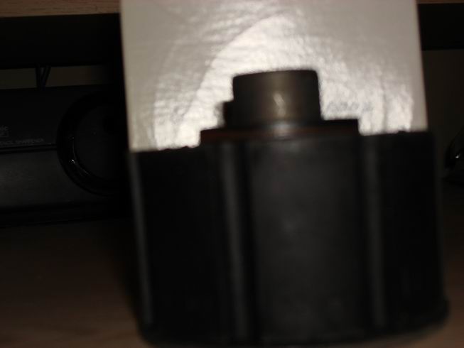 Close-up of a black plastic automotive part with a metal shaft protruding from the top
