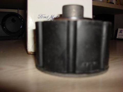 1984 Ford Bronco - A black rubber part with ribbed sides and a cylindrical top is shown on a wooden surface.