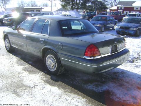 2001 Ford Crown Victoria - A dark green 2001 Ford Crown Victoria sedan is parked in a snowy lot with other vehicles visible in the background.