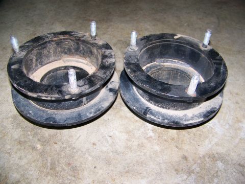 2001 Dodge 1500 - A pair of black suspension lift spacers with visible bolts are shown on a concrete surface.