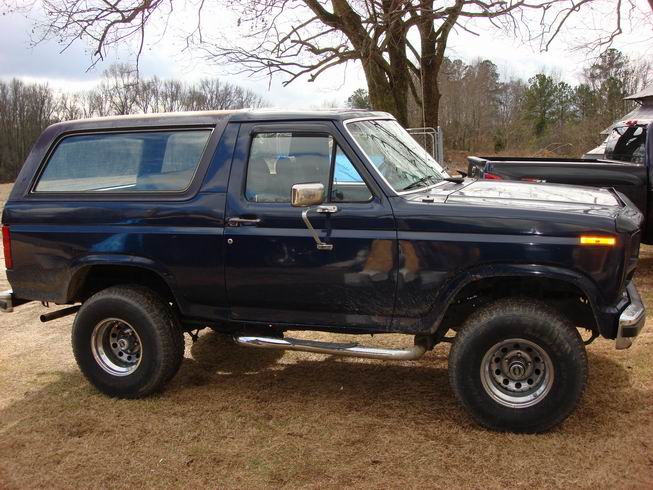 Dark blue two-door Ford Bronco side profile with hardtop and side steps