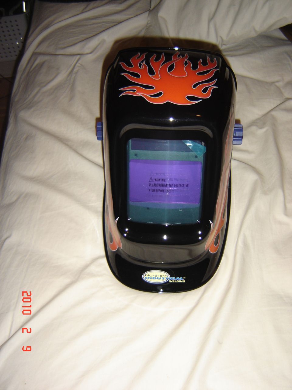 Black welding mask with orange flames and a "Northern Industrial" logo
